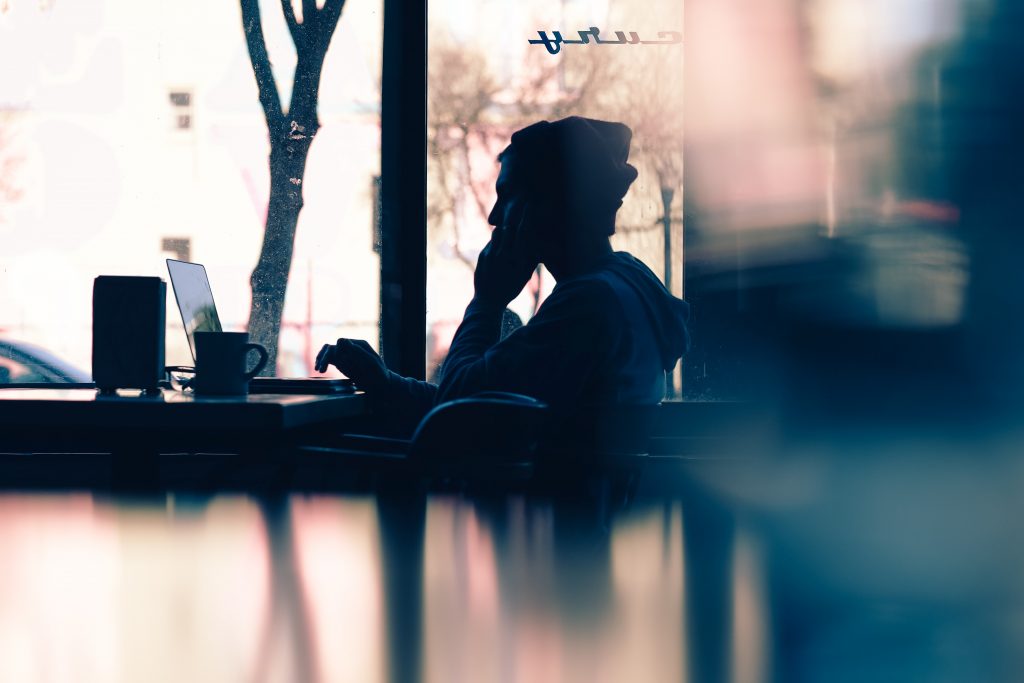 Person Sitting in Cafe Working on a Laptop